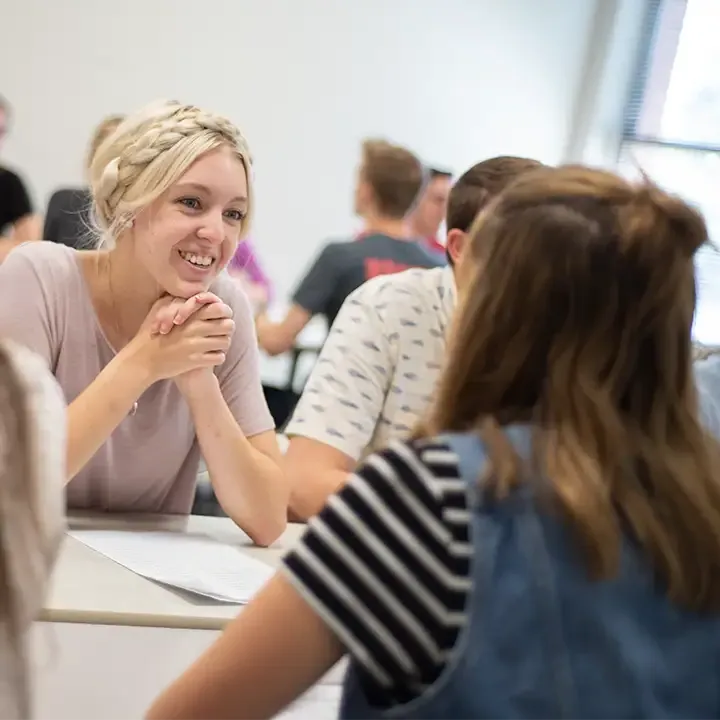 Woman smiling in room full of people.